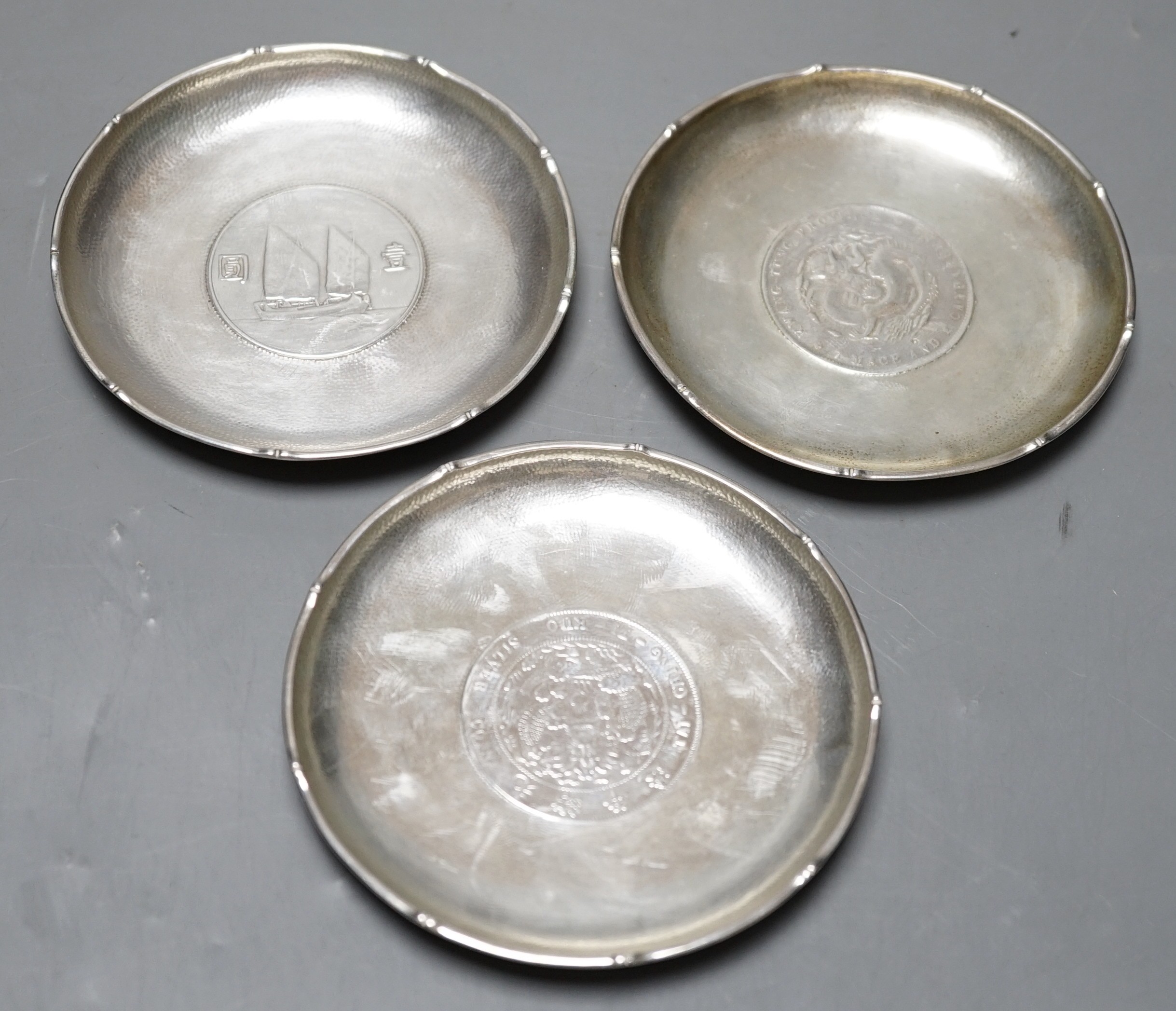 Three Chinese white metal dishes, each inset with coin, maker HC, 94mm, 196 grams gross.